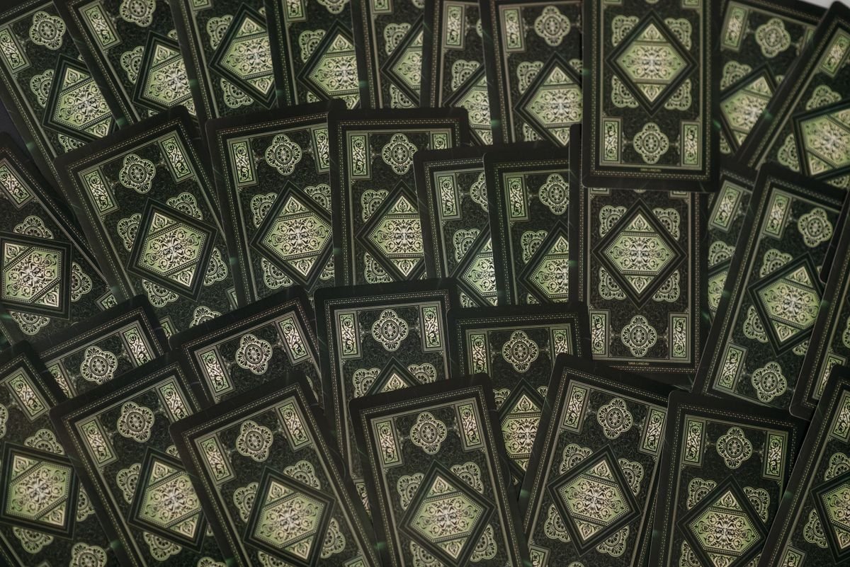 flatlay of tarot cards with intricate green patterns for online tarot reading